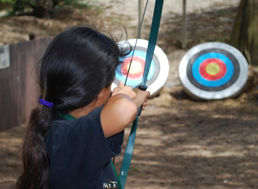 Girl doing archery at Aloha Beach Camp's Hawaii overnight program. 