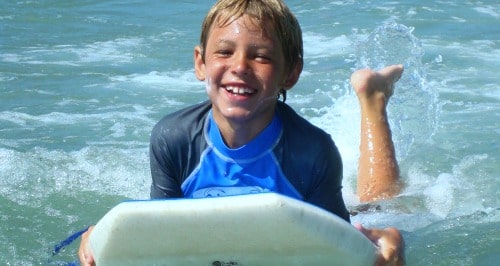 Boy smiling on his boogie board at Aloha Beach Camp Summer Day Camp in Los Angeles, CA