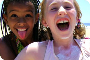 Two girls with sunscreen on smiling at beach camp