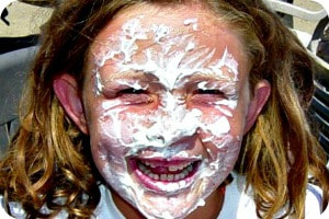 Young girl with whipped cream all over her face and smiling at camp.