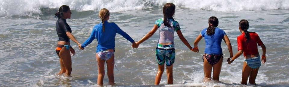 Camp counselor Frances Nelson and four female campers making a human chain by all holding hands as they enter the ocean together. Safety in numbers!