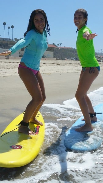 Two teenage girls learning how to surf at Aloha Beach Camp