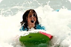 11 year old girl boogie boarding in the waves at Aloha Beach Camp's Kahuna Camp Malibu summer camp program.