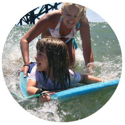 Female camp counselor helping a young girl from the San Fernando Valley learn to boogie board in the ocean at Aloha Beach Camp's summer camp program.