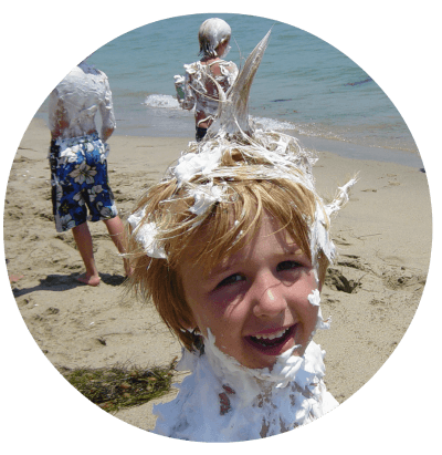 Boy standing on the beach with shaving cream all over his body and in his hair after a 