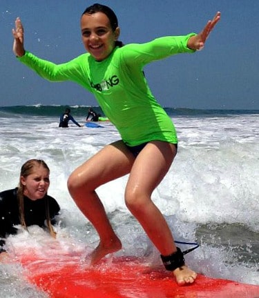 Girl surfing with her camp counselor at Aloha Beach Camp