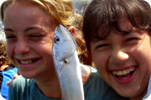 Two 12-year old girls fishing at summer camp.