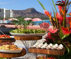 Luau food and buffet at Waikiki Beach with Diamond Head in the background.