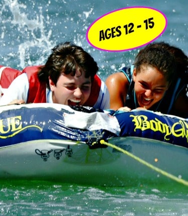 Two teenagers tubing at Aloha Beach Camp's Castaic Lake activity location.