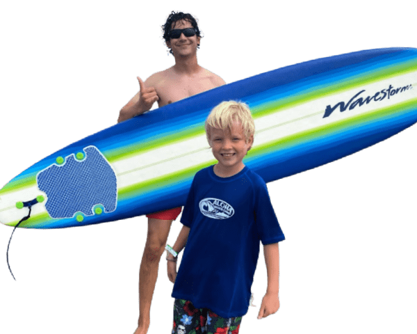 Surf camp counselor holding a surfboard with happy camper standing in front