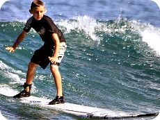 Kahuna camper boy surfing a 2-foot wave at Zuma Beach at Aloha Beach Camp's Los Angeles summer camp program.