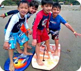 Four boys from the San Fernando Valley playing on their boogie boards at Aloha Beach Camp's Paradise Cove, Malibu summer camp location.