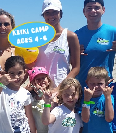 Keiki Campers learning to surf with her camp counselor at Aloha Beach Camp.