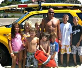 Summer camp kids from the San Fernando Valley standing with a Lifeguard and his truck on Zuma Beach.