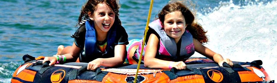 Two happy Kahuna camp girls tubing at Aloha Beach Camp's Castaic Lake activity location.