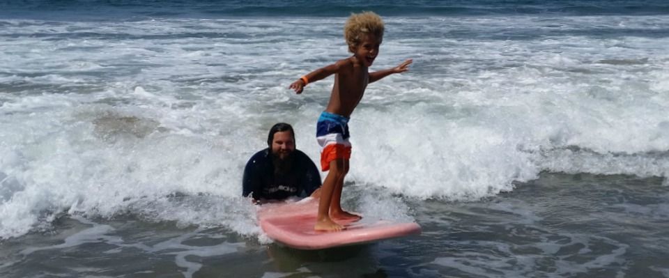 Camp director and surf instructor Matthew Duda teaches camper Mateo how to surf.
