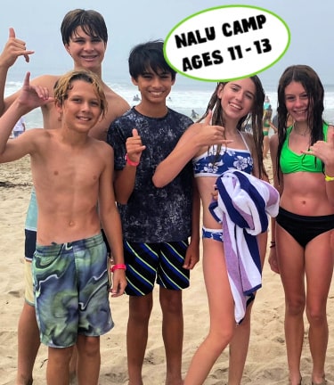 Five teenagers on the beach at Aloha Beach Camp giving the 