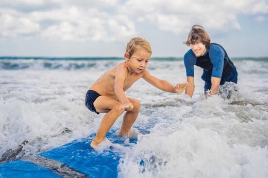 Boy learning to surf at beach camp