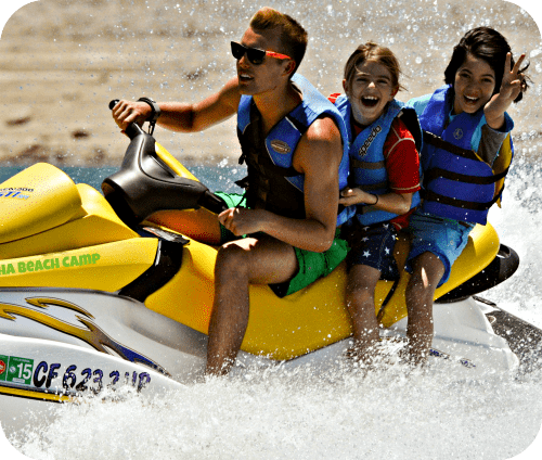 Two campers from Westwood enjoying a jet ski ride with their Camp Counselor at Aloha Beach Camp.