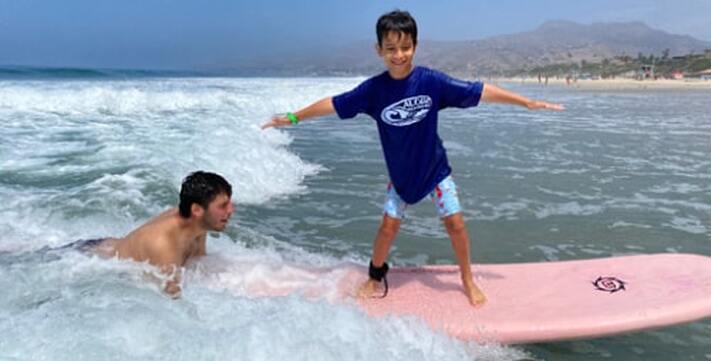 Camp instructor Yoav teaching Kahuna camper how to surf at Zuma Beach, Malibu