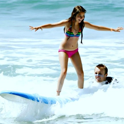 12 year old girl learning to surf with her surfing instructor camp counselor at Aloha Beach Camp.