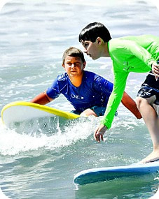 Two boys from Cheviot Hills on surfboards in the ocean at Aloha Beach Camp's Zuma Beach summer camp
