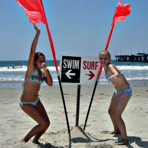 Two girls from Agoura Hills at Aloha Beach Camp's summer day camp standing on the beach in front of a 