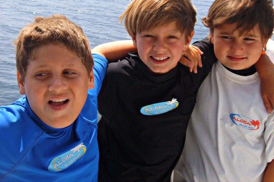 Three boys on a boat with arms around each other wearing Aloha Beach Camp t shirts and rash guards on the camp's Farewell Cruise in Marina del Rey