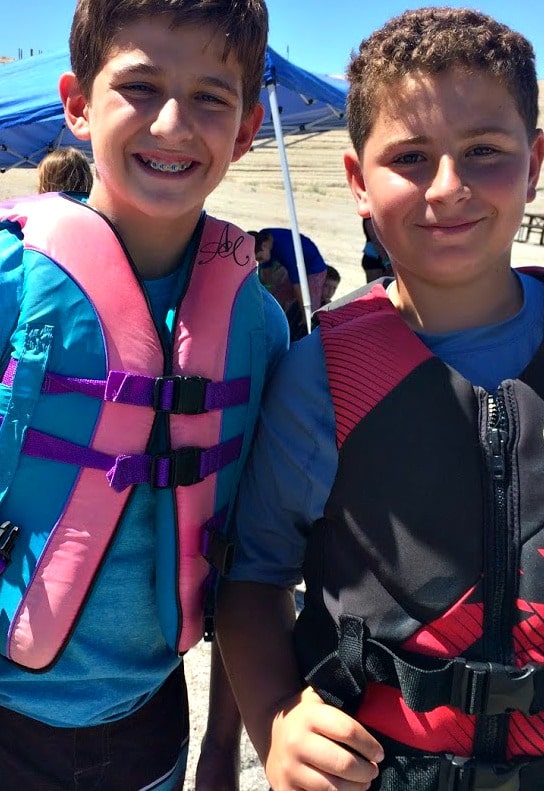 Two Aloha Beach Camp campers (teenage boys) standing together with lifejackets on getting ready to go jet skiing at Castaic Lake.