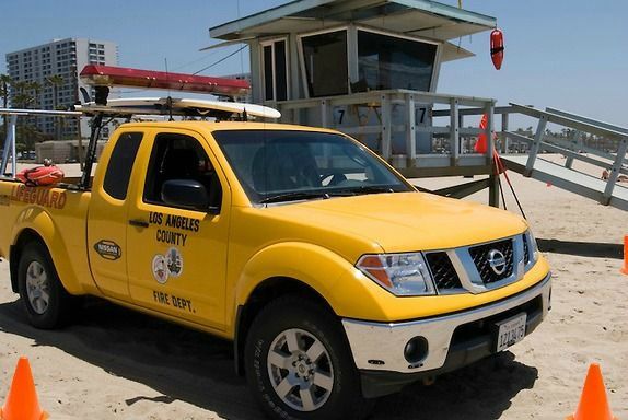 Los Angeles County Lifeguard truck surrounded by orange cones on the beach at Lifeguard Tower 7 on Zuma Beach.